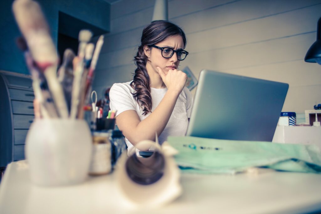 Foto de uma jovem estudante pensando em frente ao notebook